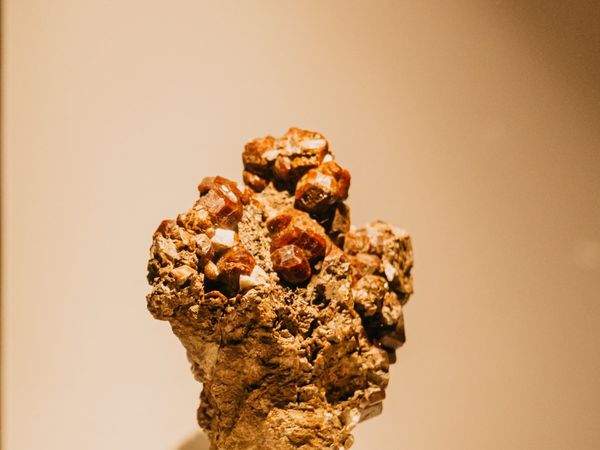 A golden crystalline mineral specimen on a plinth, lit against a dark background.