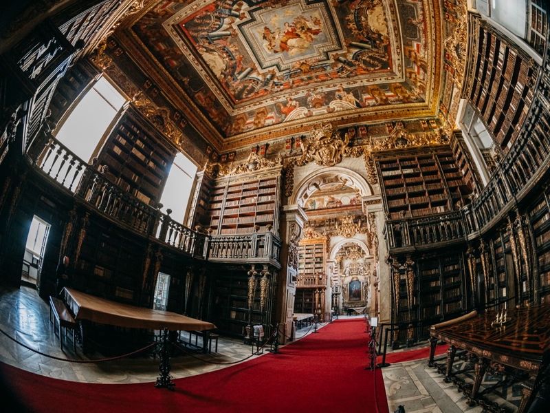 The interior of the Joanina Library in a single wide view, gilded shelves on every wall.