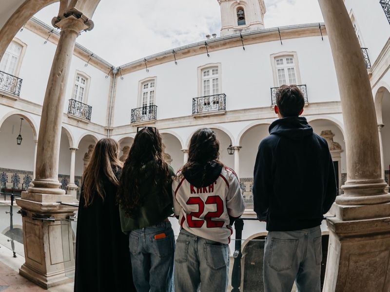 Visitors walking under the arcade of the Paço das Escolas.