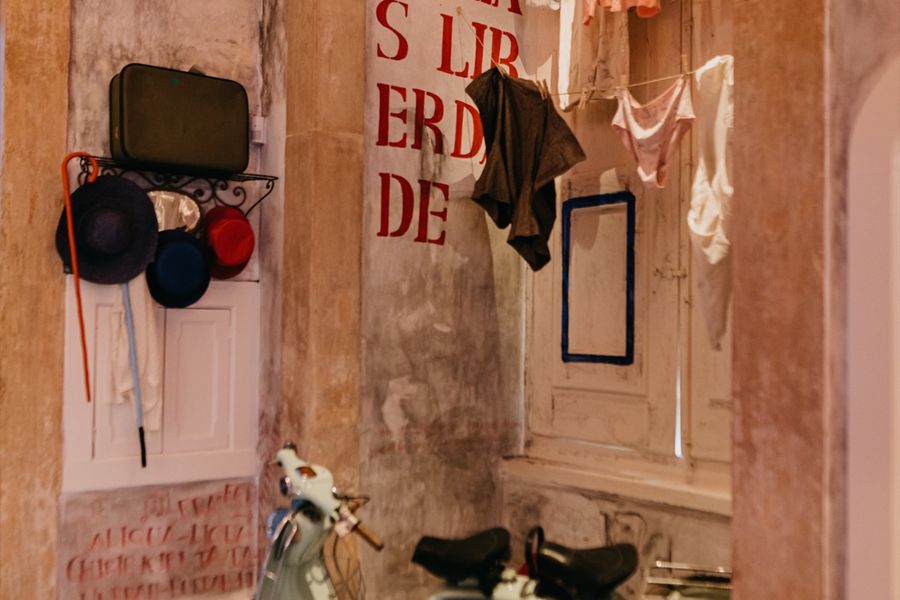 Student hats and a cape hanging beside a painted wall in the Academic Museum.