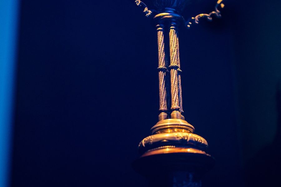A gilded ceremonial cup lit against a deep blue background.